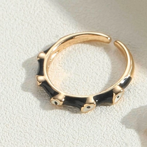 Macro view of gold adjustable ring with black enamel and white evil eye motifs