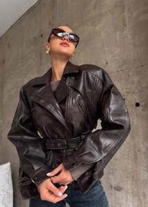 Detailed close-up of dark brown faux leather jacket with oversized lapel and waist belt