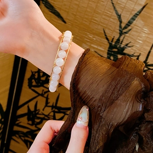 Close-up of tiger eye and white crystal beaded bracelet on a wrist with retro aesthetics