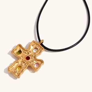 Detail of 18K gold-plated hammered cross pendant with colorful gemstones and black cord