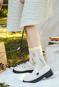 Detail of white mesh socks with pink tulip prints and yellow wavy edges for women