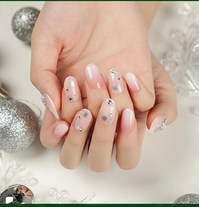 Detailed close-up of pink gradient press-on nails with silver snowflakes and pearls