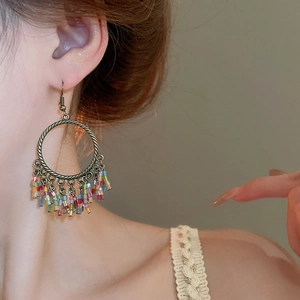 Detail of bohemian hoop earrings with multicolor beaded tassels on a model