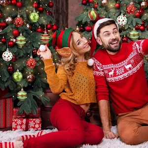 Holiday scene featuring a couple decorating a Christmas tree with red and green ornaments