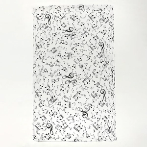 Close-up of white chiffon scarf featuring dense black musical note prints and texture