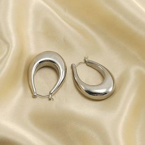 Macro shot of polished silver teardrop earrings on elegant champagne satin fabric