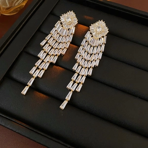 Detail of gold-plated tassel earrings with rectangular zircons on black velvet base
