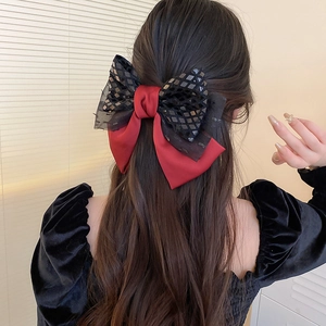 Detail of red satin and black sequin lace bow hair clip worn by a model on back of head