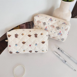 Quilted beige pencil cases with cute bear and elephant patterns on a white table