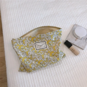 Detail of yellow floral cotton cosmetic bag with label on quilted texture background