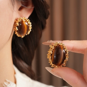 Detail of vintage tiger eye earrings with gold grain edges and a model wearing the studs