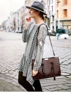 Macro detail of dark brown crocodile embossed leather tote bag with silver hardware accents