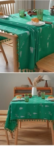 Detail of green Christmas tablecloth with white deer embroidery and tassel fringes