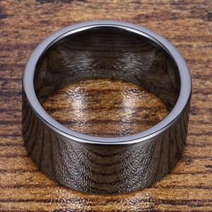 Dettaglio dell'anello nero da 12mm con finitura a specchio su una base in legno rustico