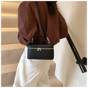Detail of black lychee grain leather box bag with silver zippers and top handle