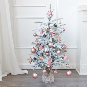 Mini pink flocked Christmas tree with snow, ornaments and a rustic burlap base