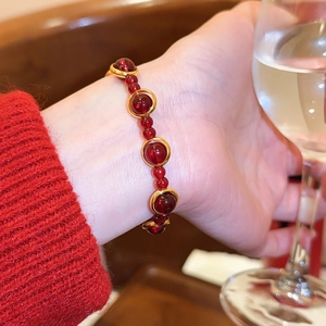 Nahaufnahme eines roten Achat-Armbands mit eleganten goldenen Akzenten am Handgelenk
