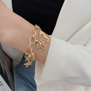 Detail of gold marine charm bracelet featuring seahorse, octopus, shell, and starfish charms