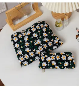 Close-up of quilted black cosmetic bag set with white and yellow daisy flower embroidery