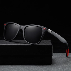 Classic matte black oversized sunglasses with red accents on a textured display box
