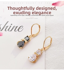 Detail of cat earrings with black and clear cubic zirconia in a golden lever-back setting