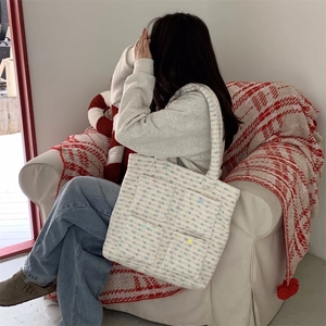 Detail of plush tweed tote bag with four small pockets shown in a cozy autumn setting