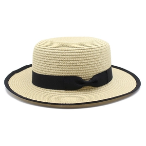 Close-up of beige straw boater hat featuring a black ribbon bow and matching brim piping