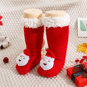 Detailed knit texture of red baby Christmas socks with 3D Santa Claus and plush cuffs