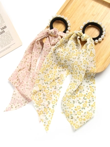 Detail of floral chiffon ribbon hair ties with white pearls on a light wooden tray