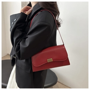 Detail of dark red rectangular shoulder bag with golden buckle on a black blazer