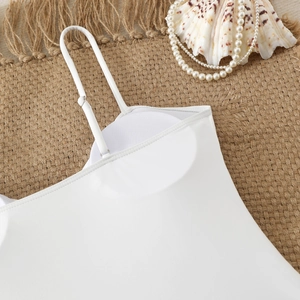 Detailed view of white slim-fit bodysuit with built-in pads on beach mat background