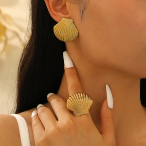 Close-up of golden shell-shaped earrings and ring set worn on model with ocean vibes