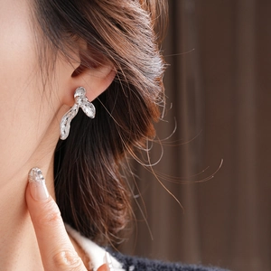 Detail view of silver orchid petal earrings with textured metal on a model