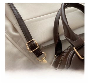 Detail of adjustable leather strap with gold buckle on a brown vintage handbag