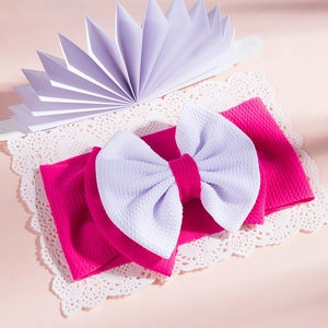 Detail of baby headband with double-layered rose red and white waffle bow on lace paper