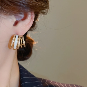 Detailed close-up of a multi-layer C-shaped gold hoop earring with pavé zircon and enamel