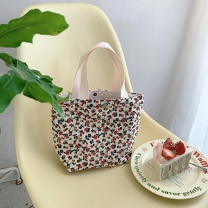 Floral corduroy handbag detail with woven handles and magnetic clasp on a chair
