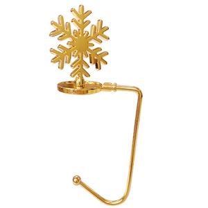 Polished golden snowflake mantel hook for Christmas stockings on a white background