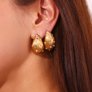 Gros plan sur des boucles d'oreilles goutte dorées 18K avec cristaux et perles