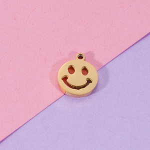 Close-up of golden smiley face hollow pendant on a pink and purple backdrop