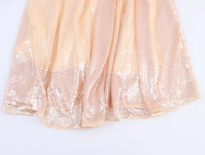 Detail of champagne gold sequined fabric with wavy hem on mesh lining for party dress