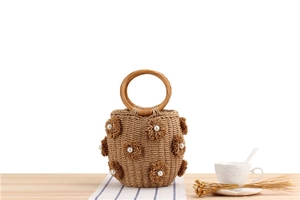Detail view of woven straw bucket bag with floral pearl charms and wooden handle