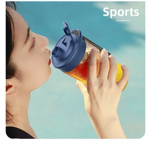 Close-up of athlete drinking orange juice from a portable blue lid juicer cup outdoors