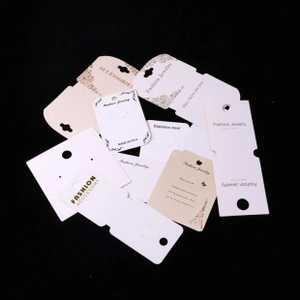 Various white and beige paper jewelry display cards for earrings and necklaces on black background