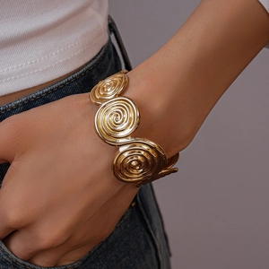 Detailed close-up of a wide golden spiral cuff bracelet showing metallic texture and shine