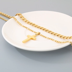 Vue détaillée montrant le pendentif croix en or poli et le collier à mailles gourmette