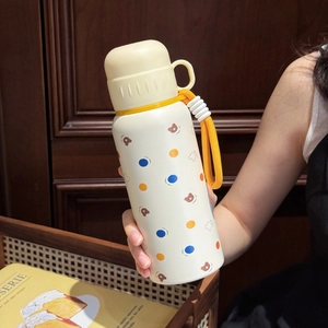 Close-up of cream stainless steel bottle with bear pattern and yellow carrying strap