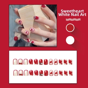 Macro view of 24pcs red and white press-on nails with sweet heart patterns and bow rhinestones