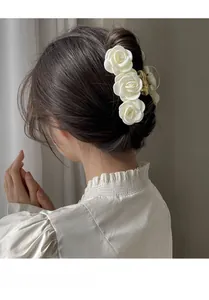 Detail of elegant large hair claw clip featuring three satin white roses for women