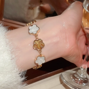Vue détaillée du bracelet floral doré avec pendentifs blancs portés par un mannequin